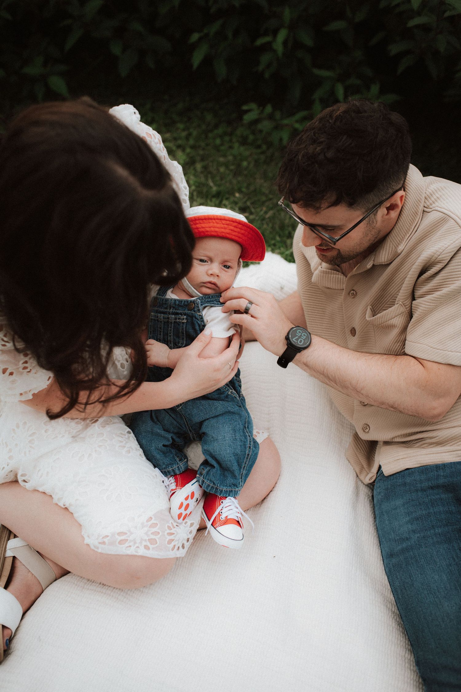 Tender family interaction captured in intimate black and white photography style on white blanket outdoors.