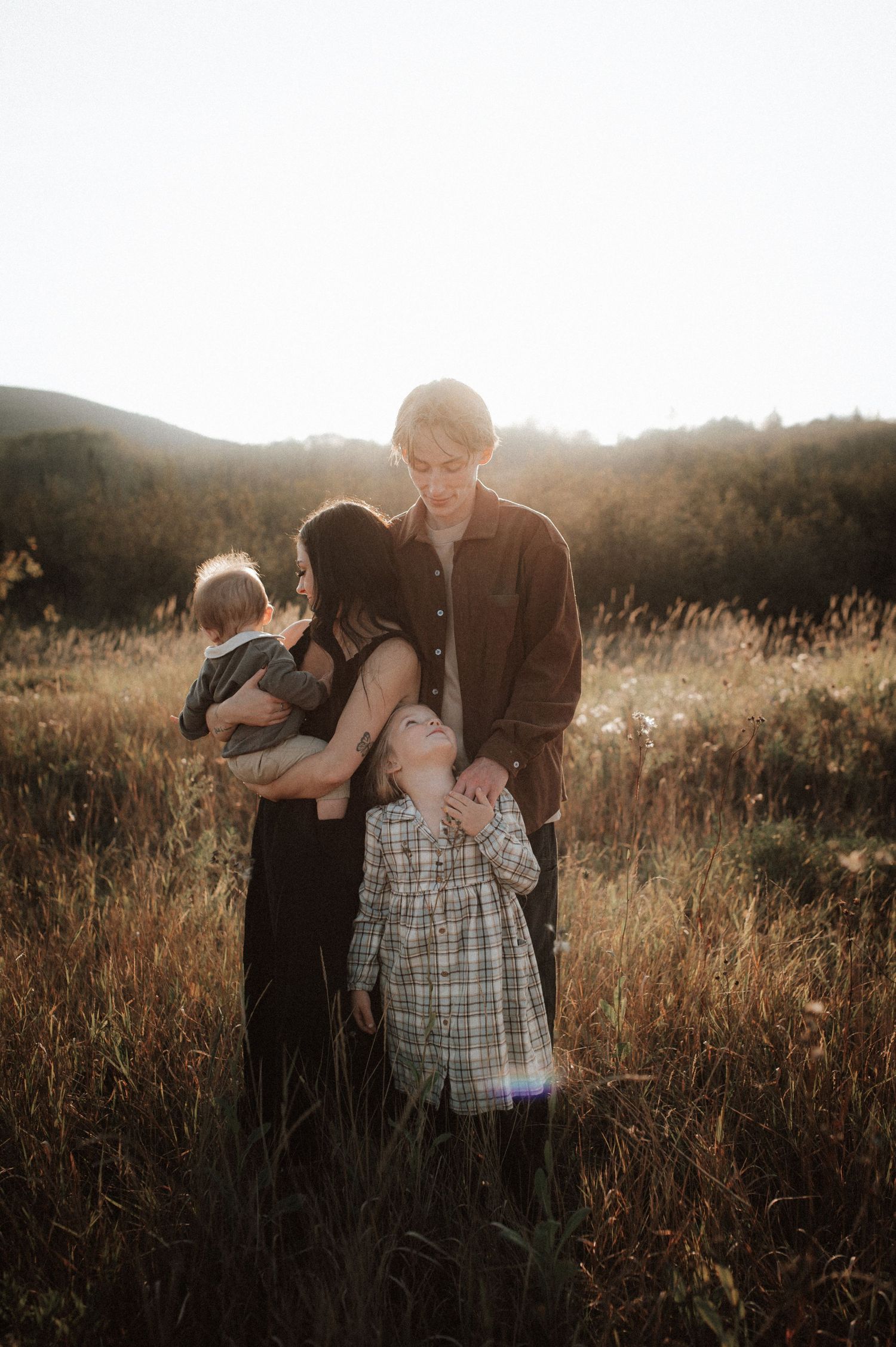 Silhouetted figures embrace in a sunlit meadow during golden hour, creating a warm and intimate outdoor moment.