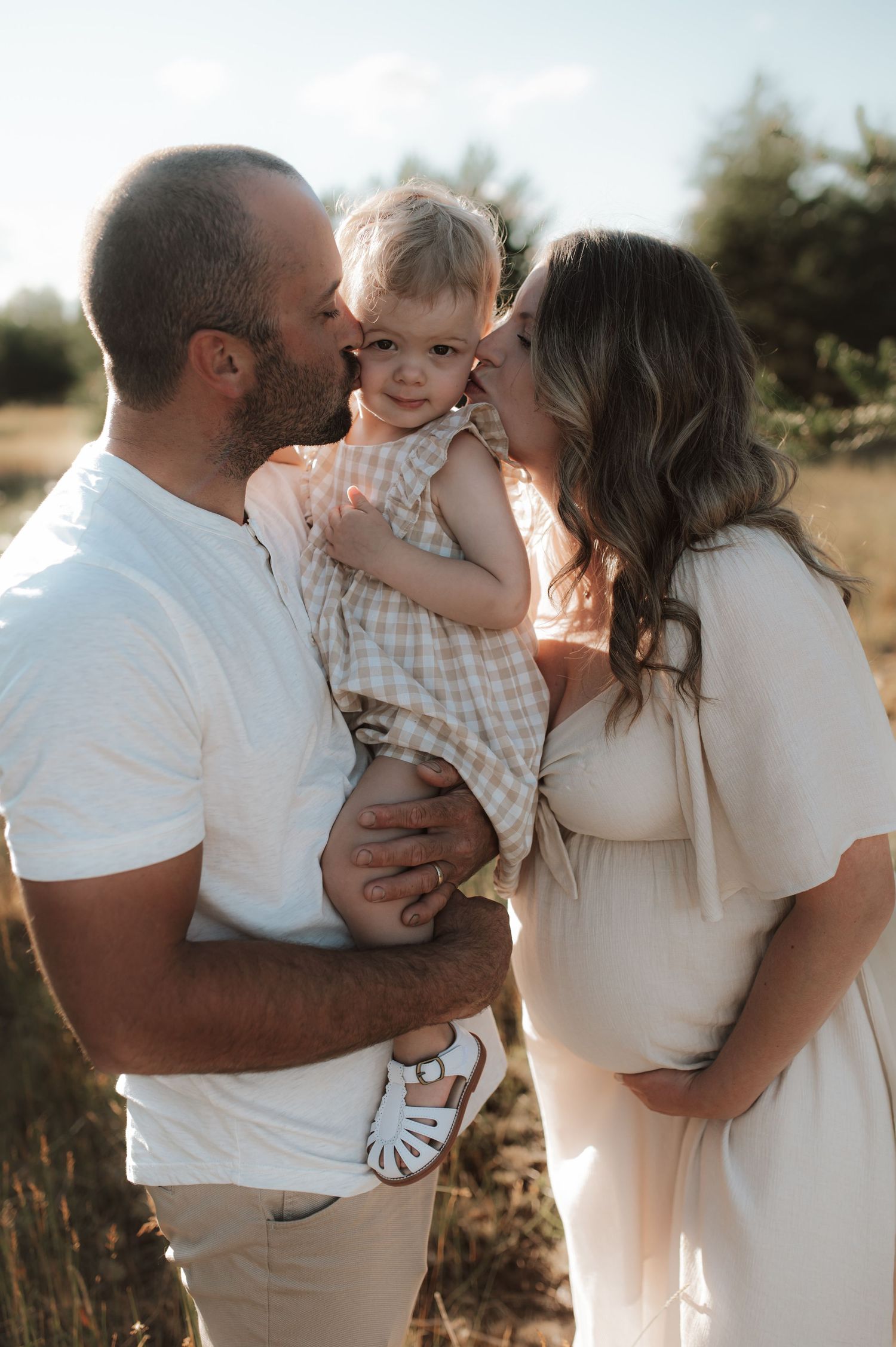 A family shares a tender moment together in a sunlit field during golden hour.