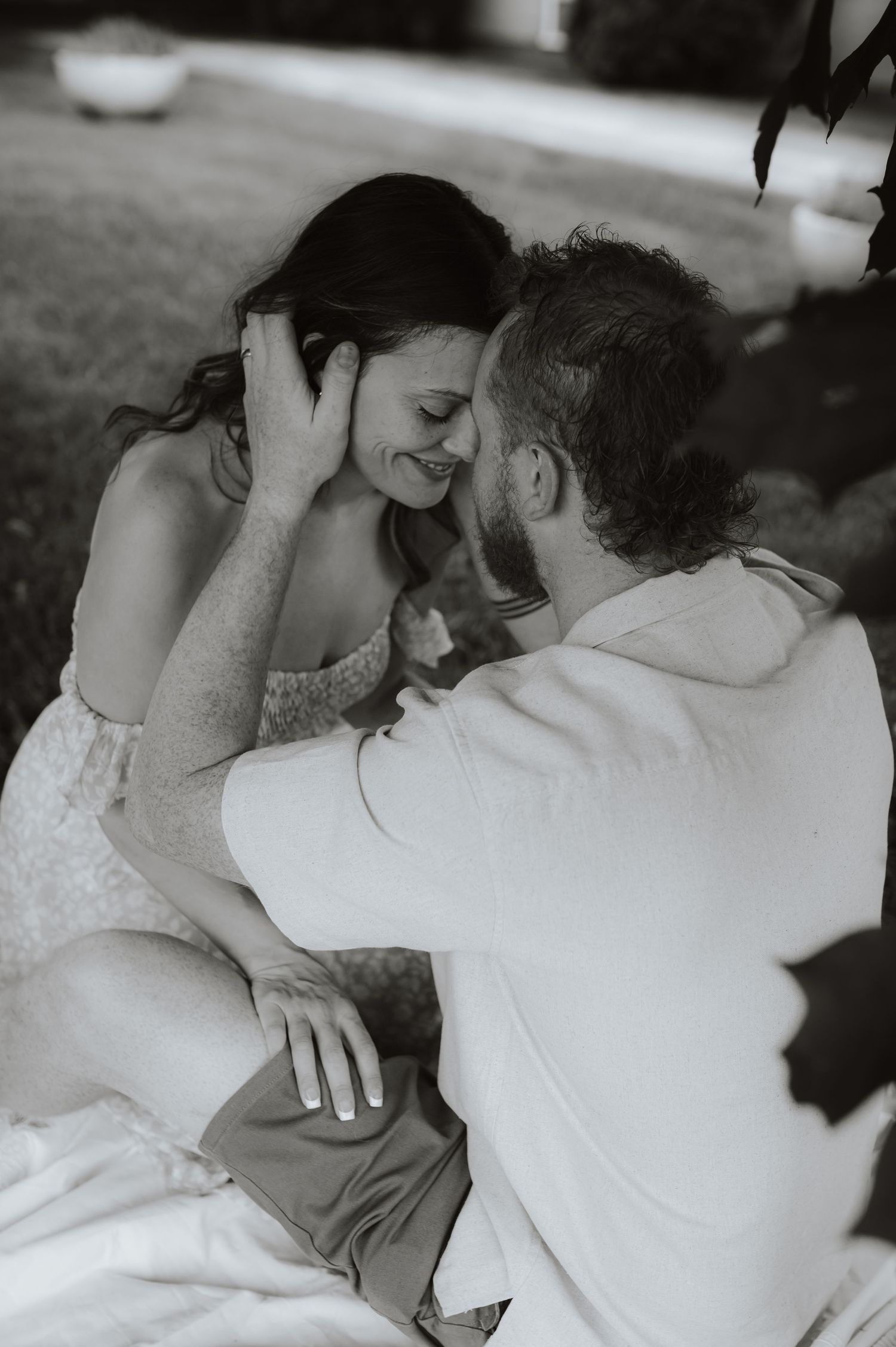 Sweet black and white photo of couple sharing an intimate romantic moment outdoors in wedding attire.