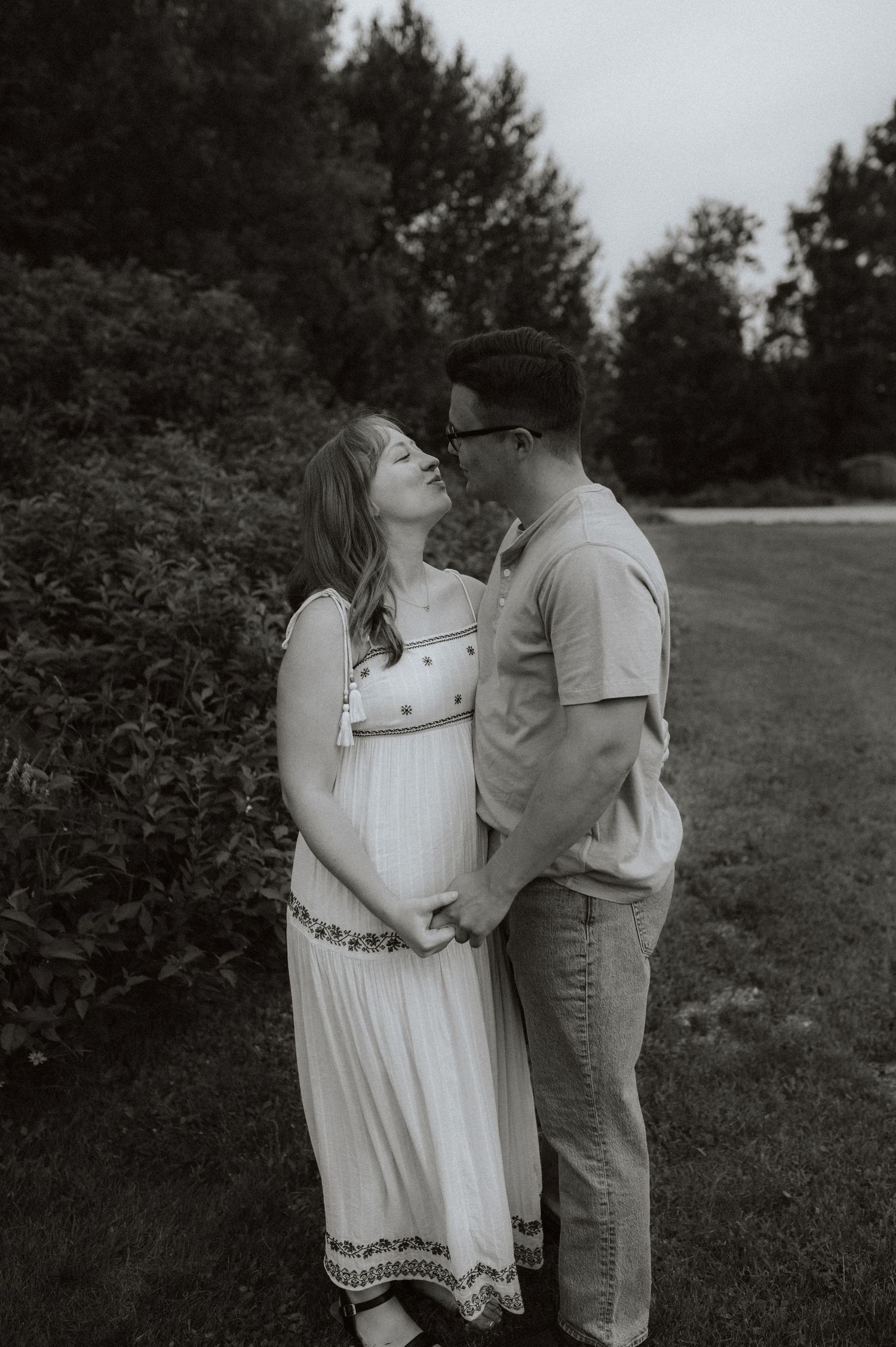 Black and white romantic maternity photoshoot captures intimate couple in a peaceful outdoor garden setting.