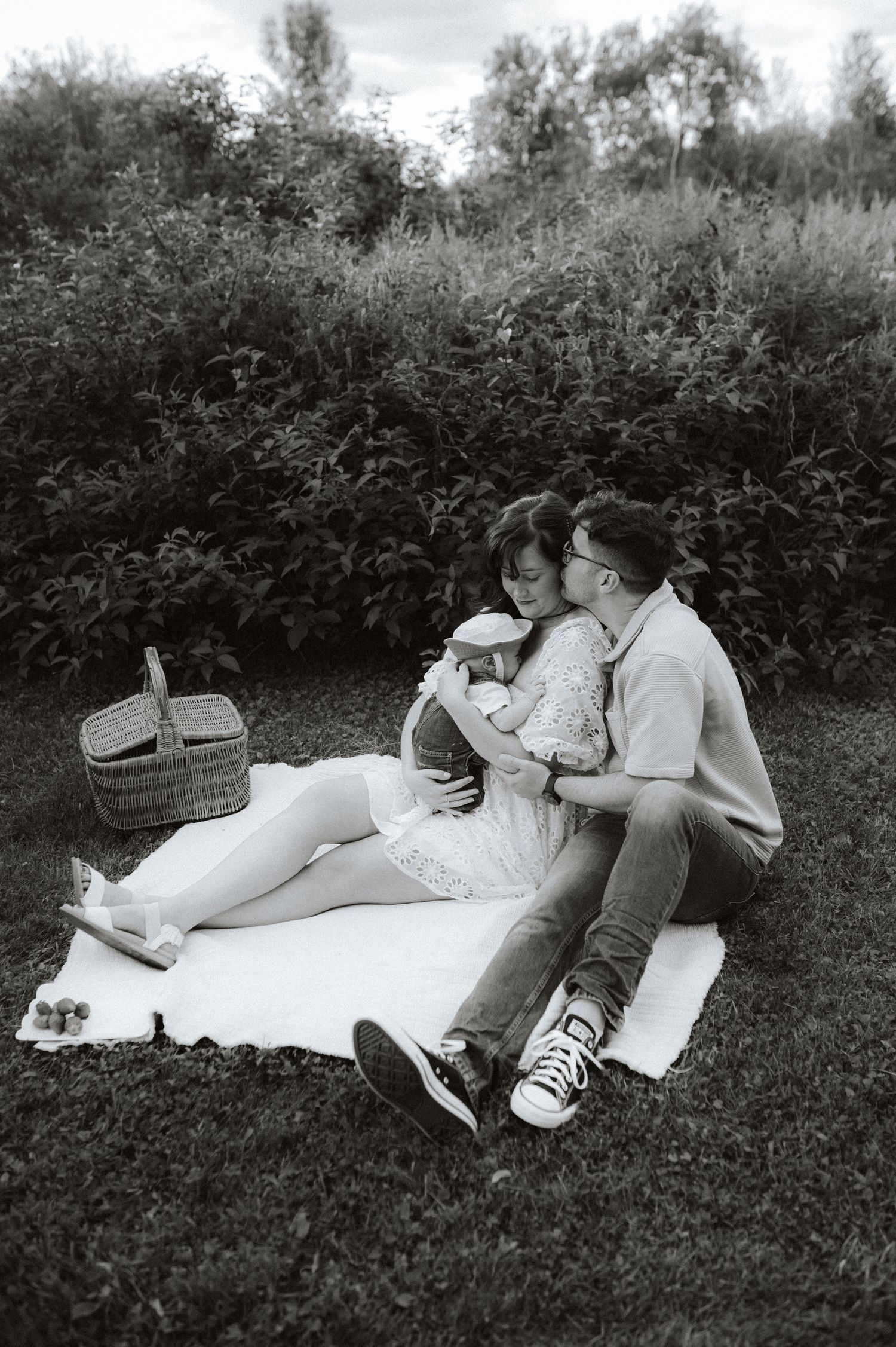 Black and white vintage photo of a couple enjoying a romantic picnic on a blanket with a wicker basket beside them.