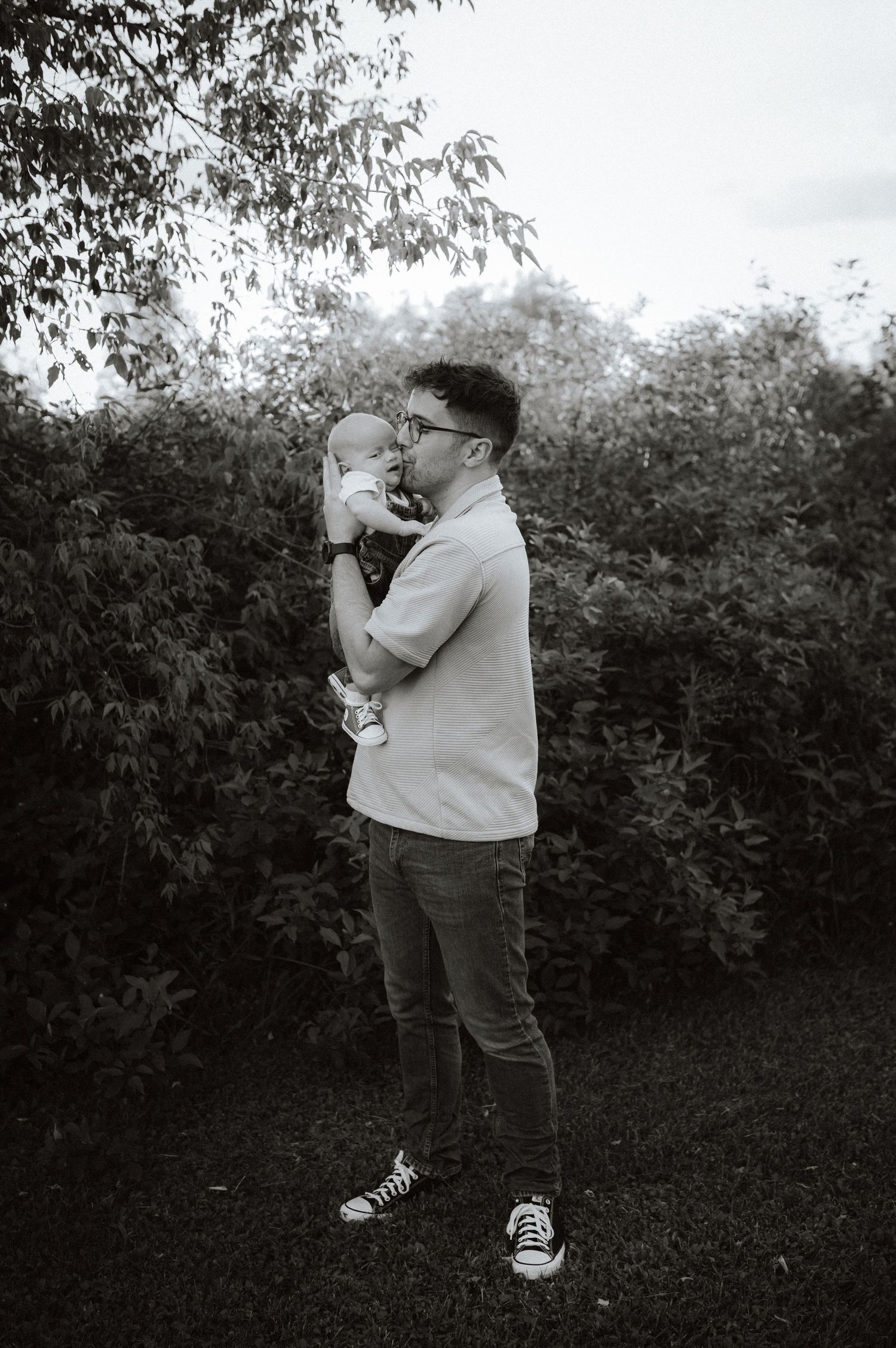 Child with glasses plays with a bubble wand in a garden, shown in a series of connected black and white photographs.