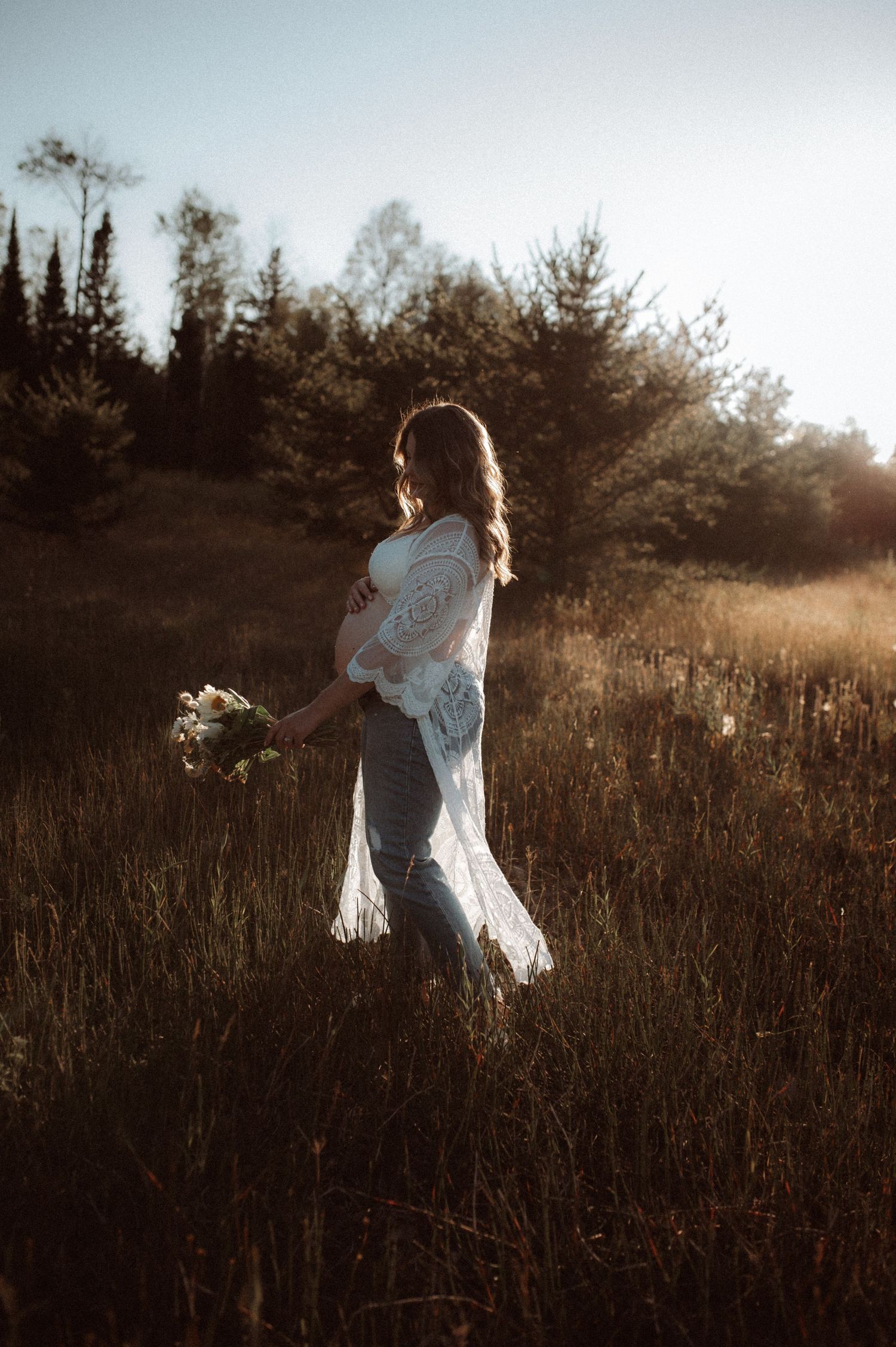 A woman in a flowing white dress dances gracefully through a golden sunlit meadow at sunset.