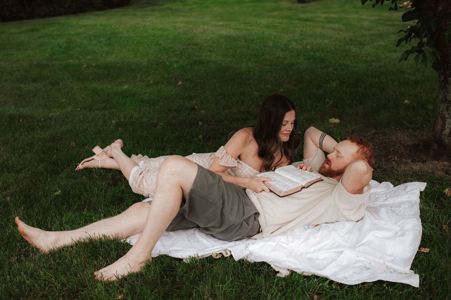 A figure in white wedding dress lying in grass during an outdoor bridal photo session.