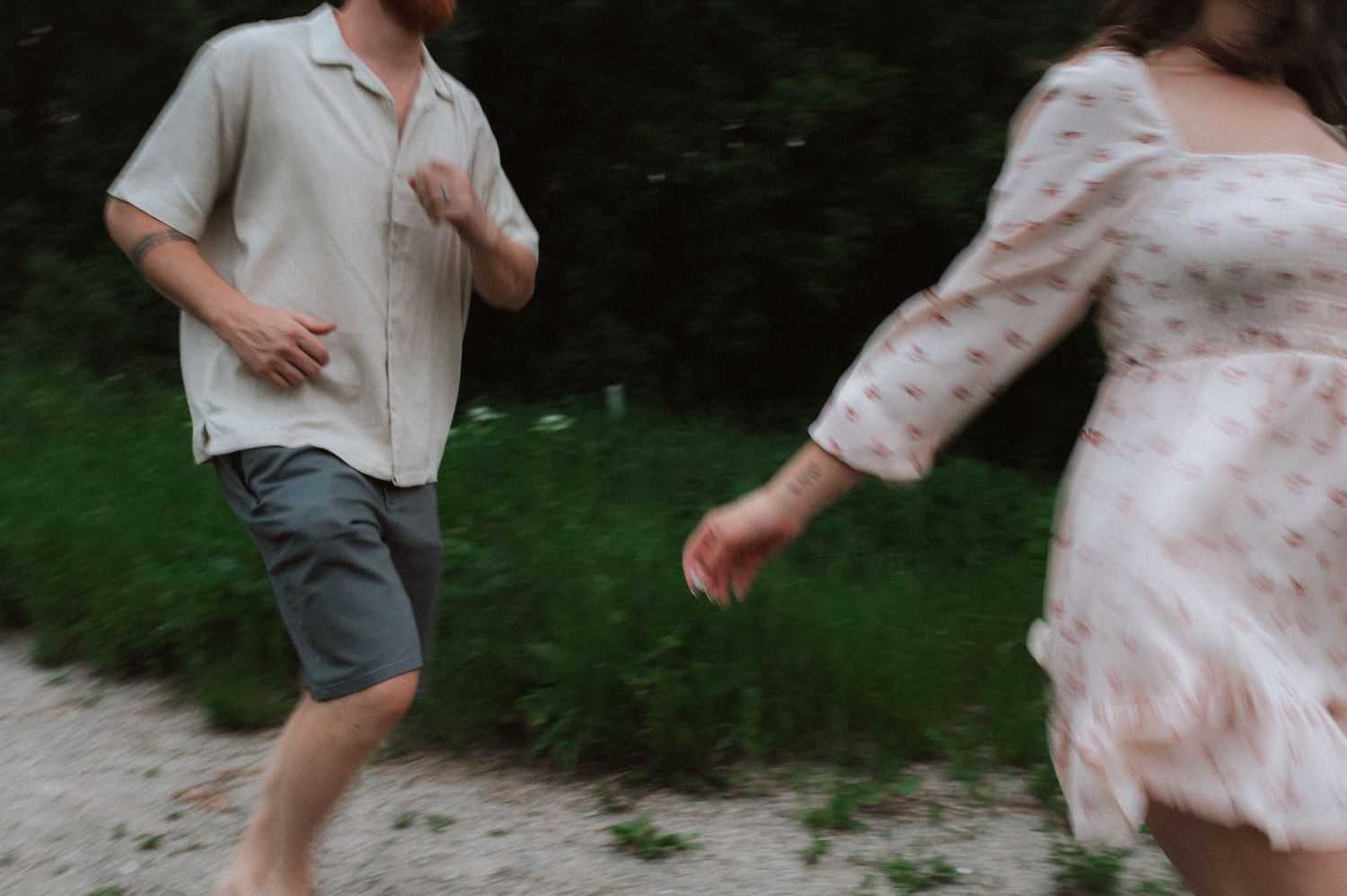 A person leaps and dances outdoors in gray shorts and light colored top with green grass and trees in background.