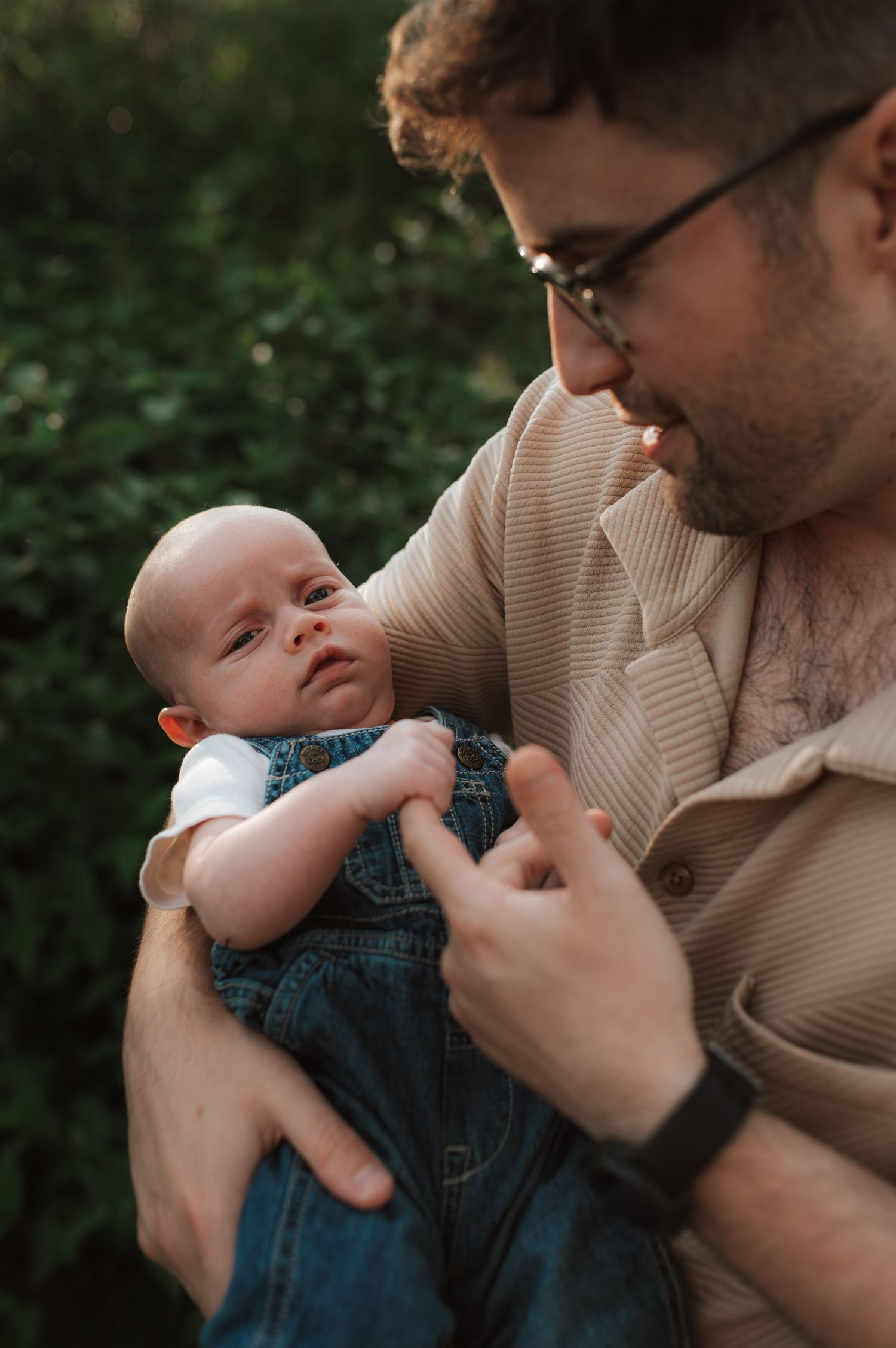 Baby in denim overalls laughs joyfully while being held in tender outdoor photo sequence.