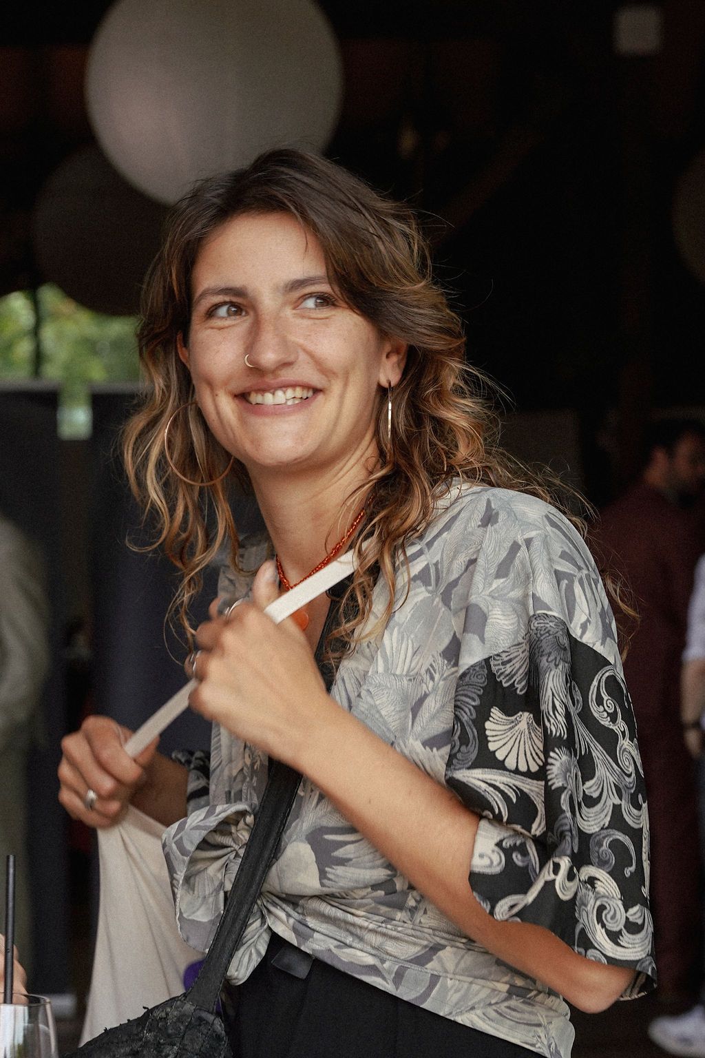 A person wearing a gray patterned shirt smiles while posing in a series of candid shots.