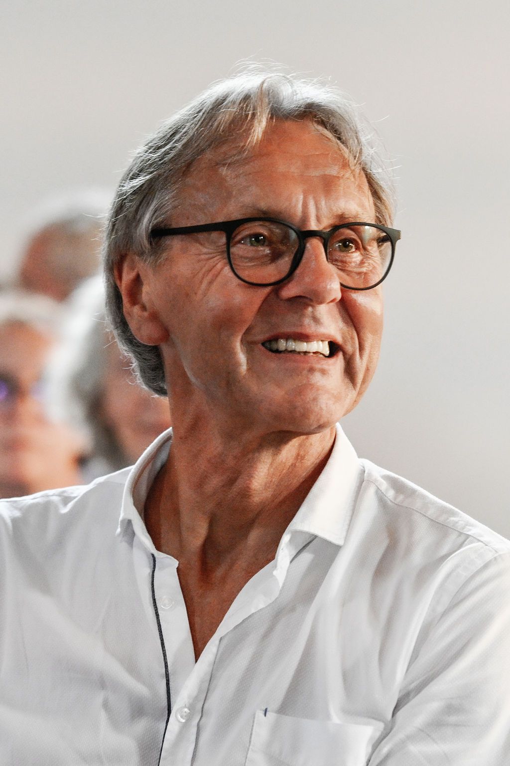 A sequence of photos showing a person in a white shirt and glasses smiling and laughing with genuine joy.