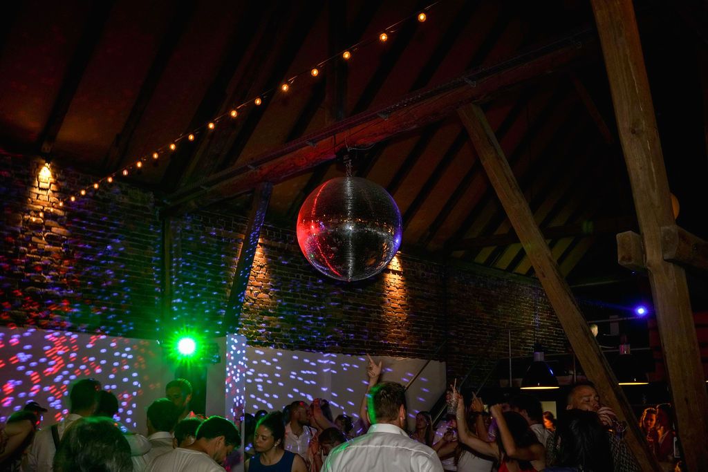A rustic barn venue decorated with string lights and colorful LED illumination creates a festive party atmosphere.