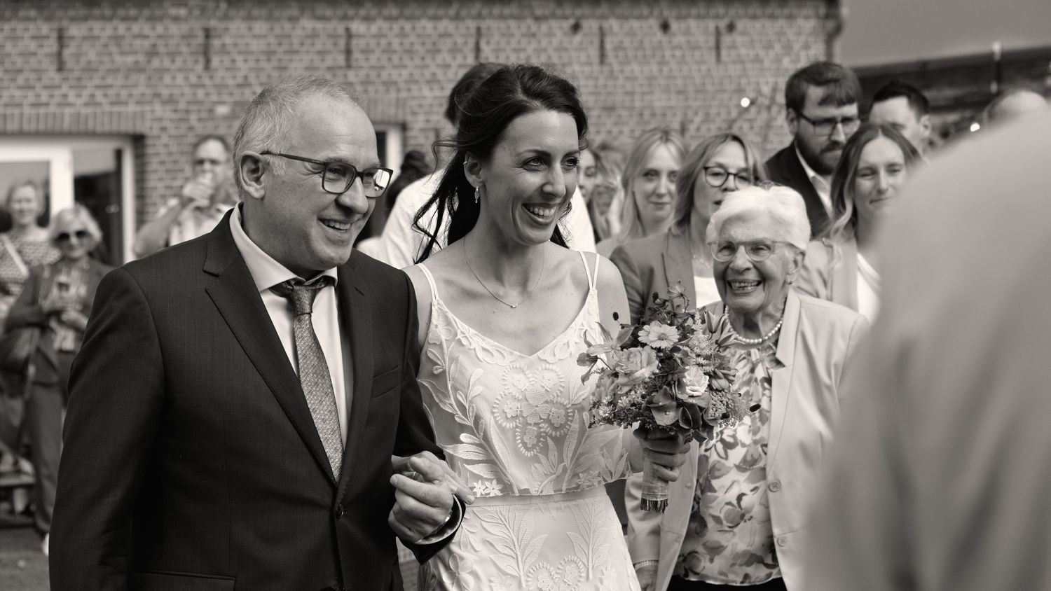 A candid black and white photo capturing joy during a wedding ceremony.