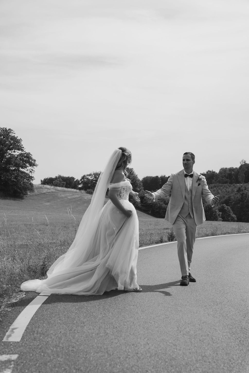 Black and white wedding photos showing a couple walking on a path with the bride's veil flowing dramatically in the wind.