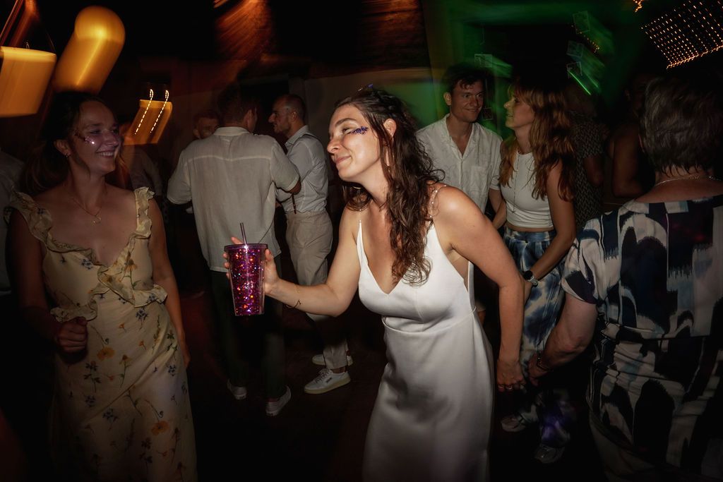 A person in a white dress dances energetically at a dimly lit nightclub party.