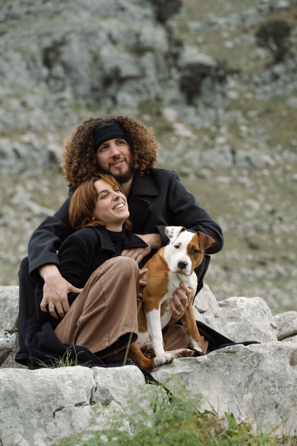 Person in black clothing relaxes on rocky terrain with a Beagle dog companion in a peaceful outdoor setting.