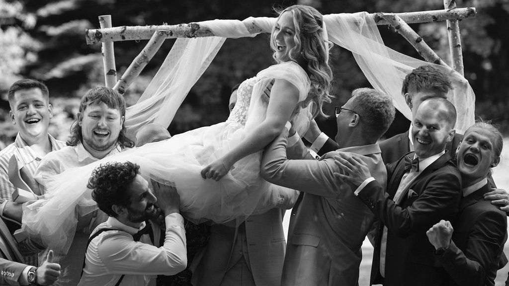Group of wedding guests celebrating and cheering together in black and white photography.