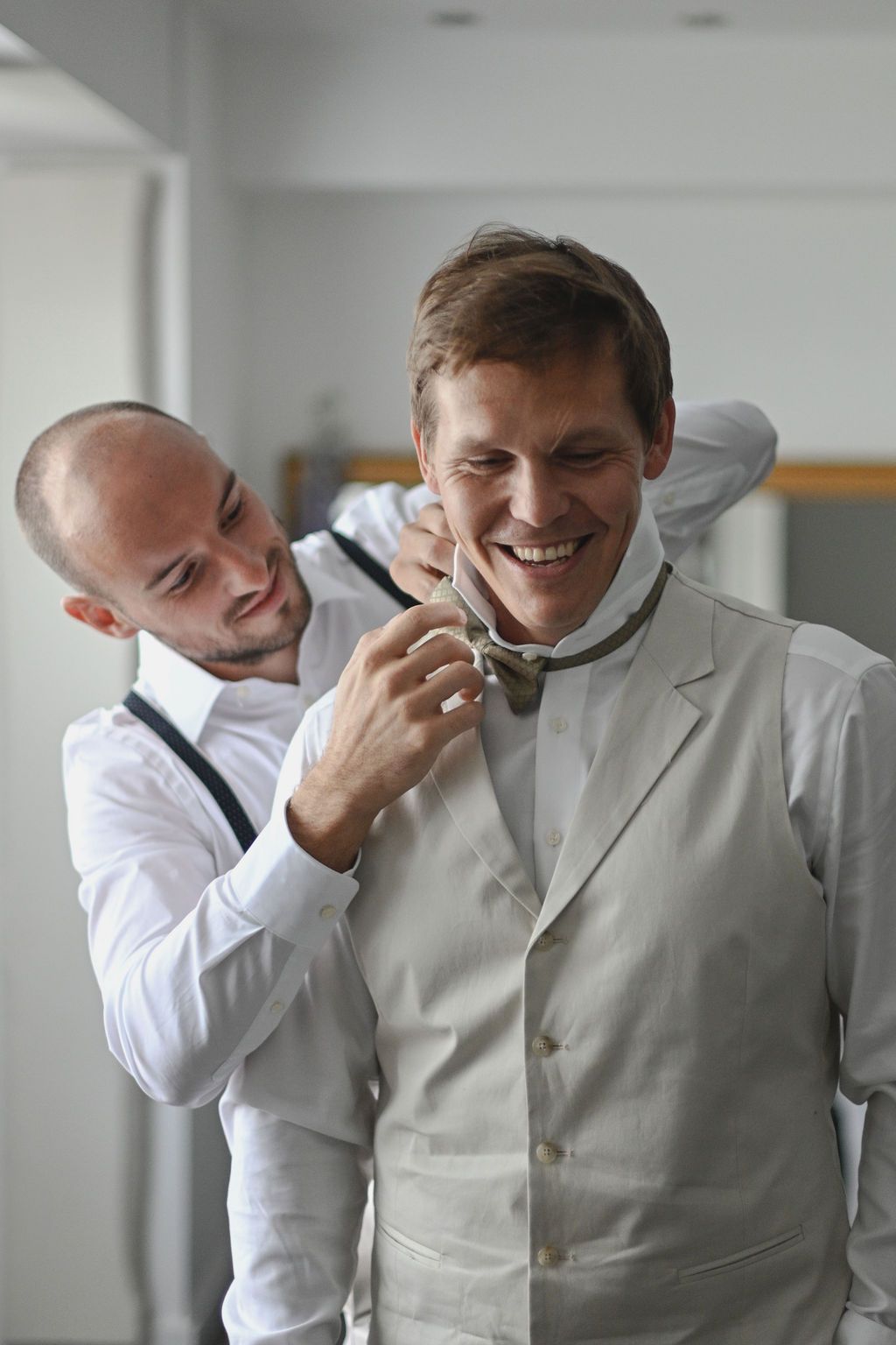 Two people in formal wear sharing a lighthearted moment and laughing together.