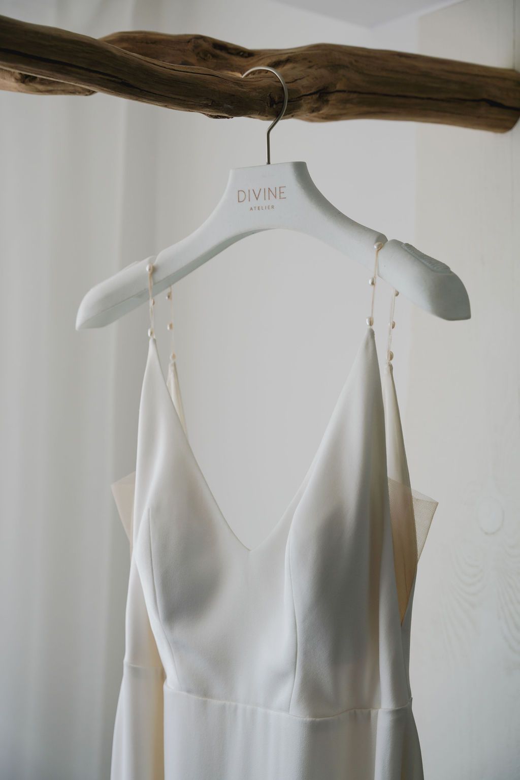 Four views of a sleek white sleeveless dress form displayed on a hanger against a light-colored wall.
