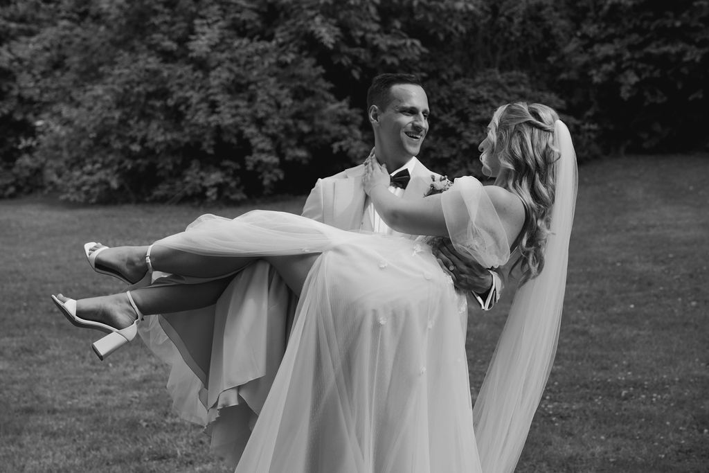 A couple dances together in a romantic outdoor setting wearing formal attire in black and white.