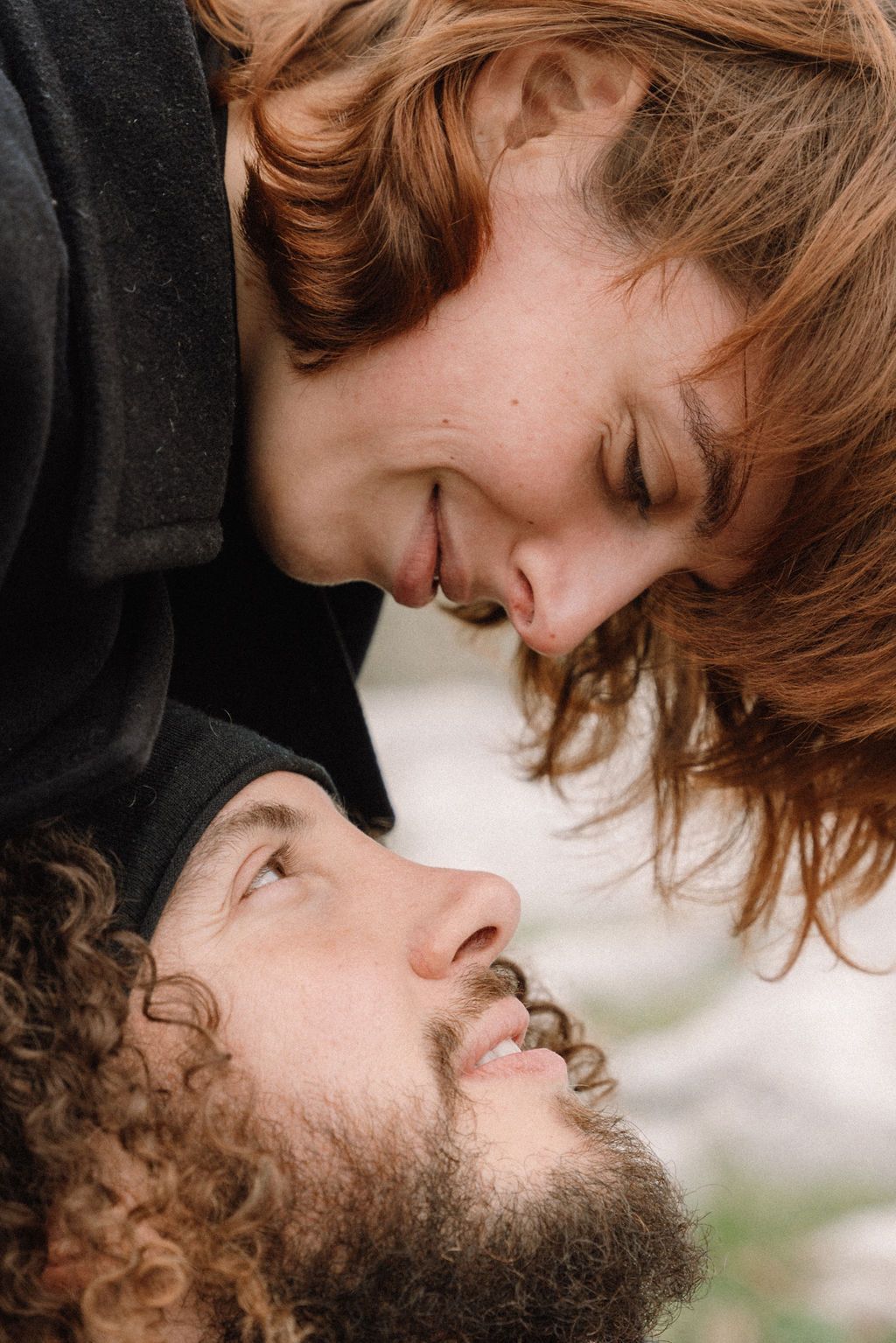 Close-up of a couple sharing an intimate moment outdoors with soft natural lighting.
