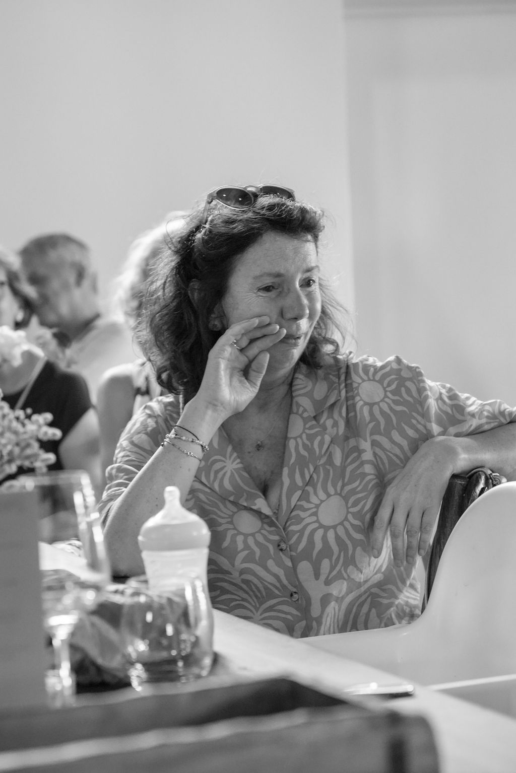 A black and white sequence shows a person in a patterned shirt resting their head in their hands at a table.
