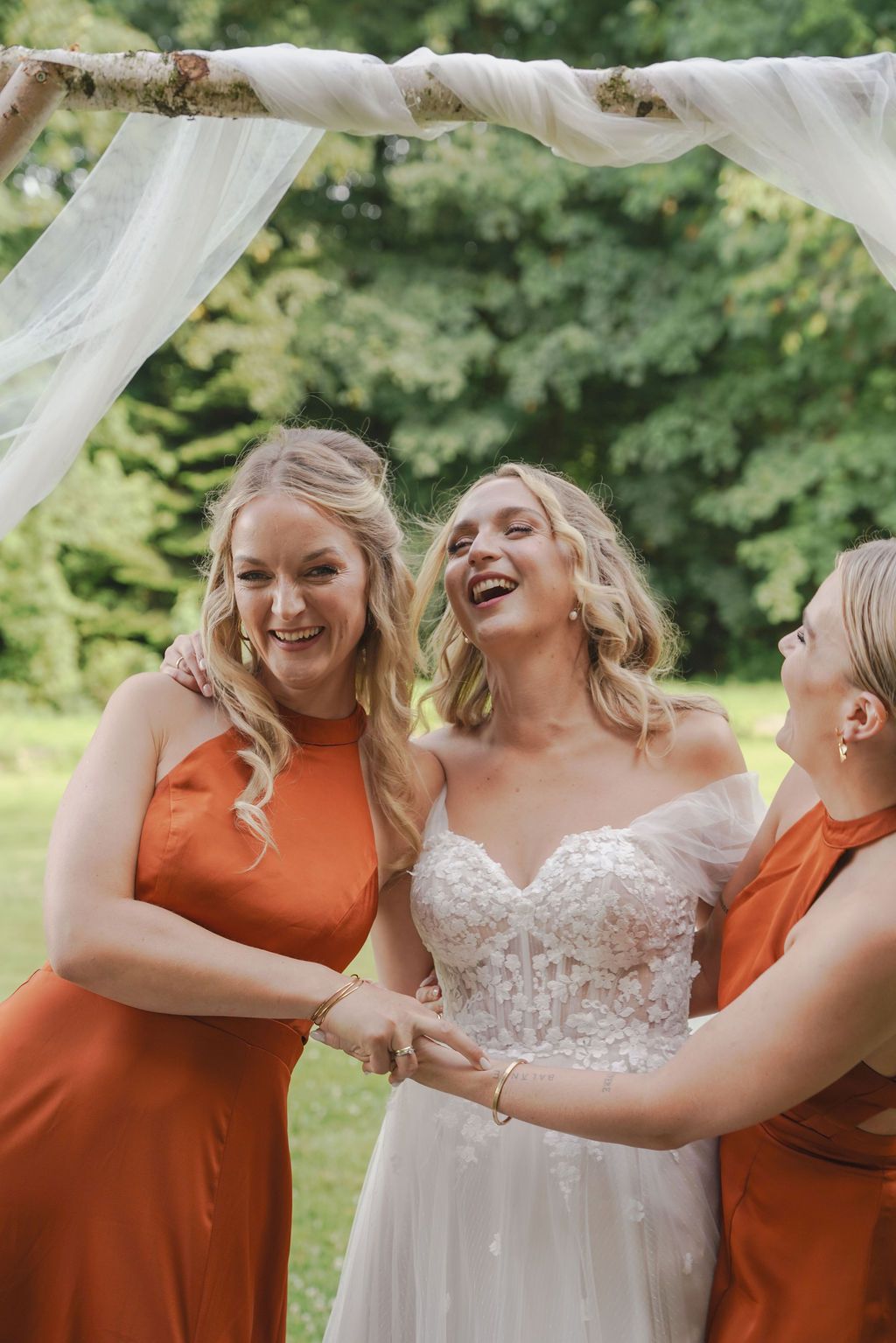 A series of candid wedding photos showing bridesmaids in burnt orange dresses sharing joyful moments with the bride.