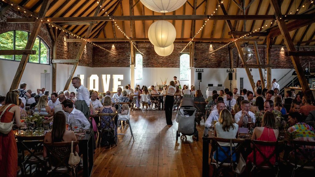 Large rustic barn venue filled with dining tables and guests for an elegant wedding reception celebration.