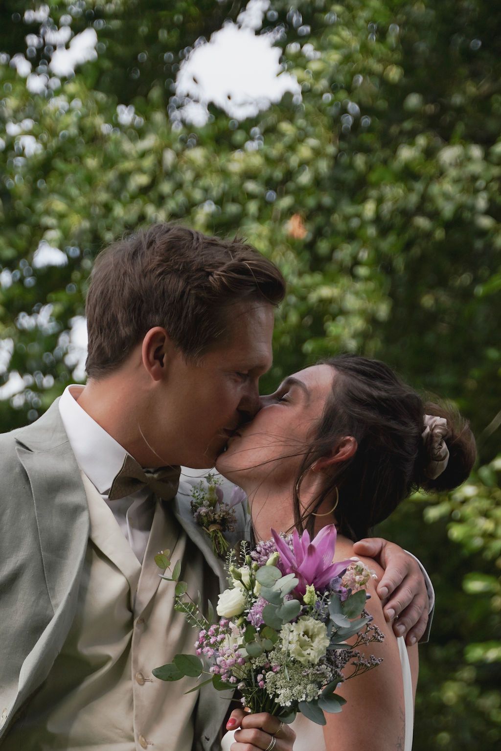 A romantic wedding couple shares three intimate kisses in a lush garden setting with floral bouquet details.