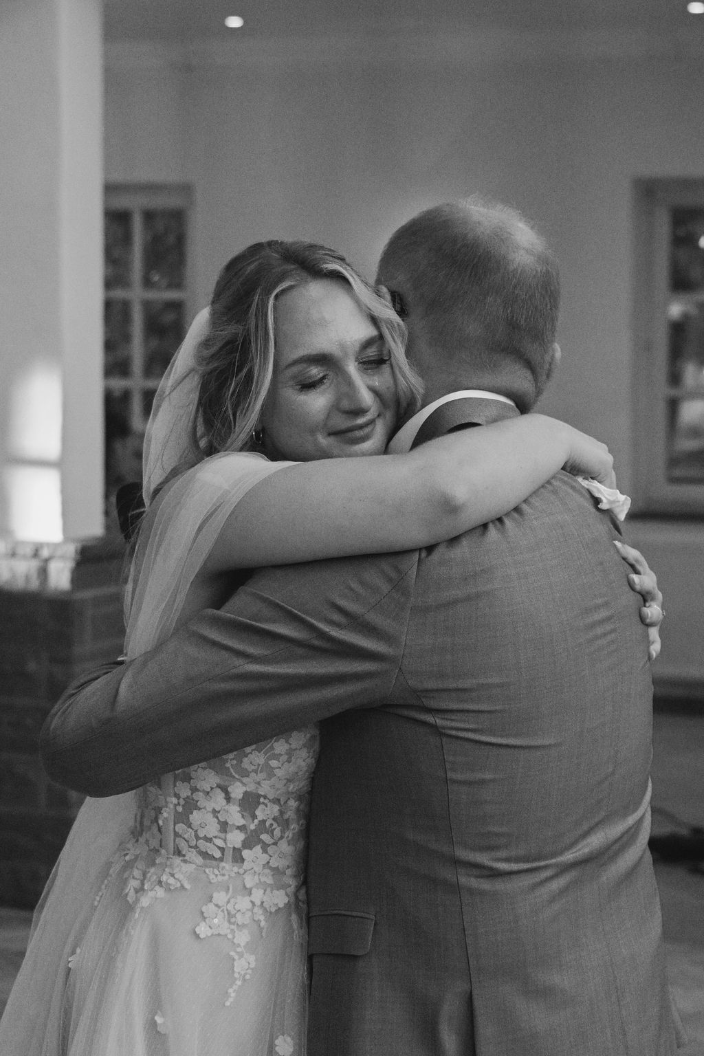 A tender black and white moment captured during a wedding dance as a bride embraces her dance partner.