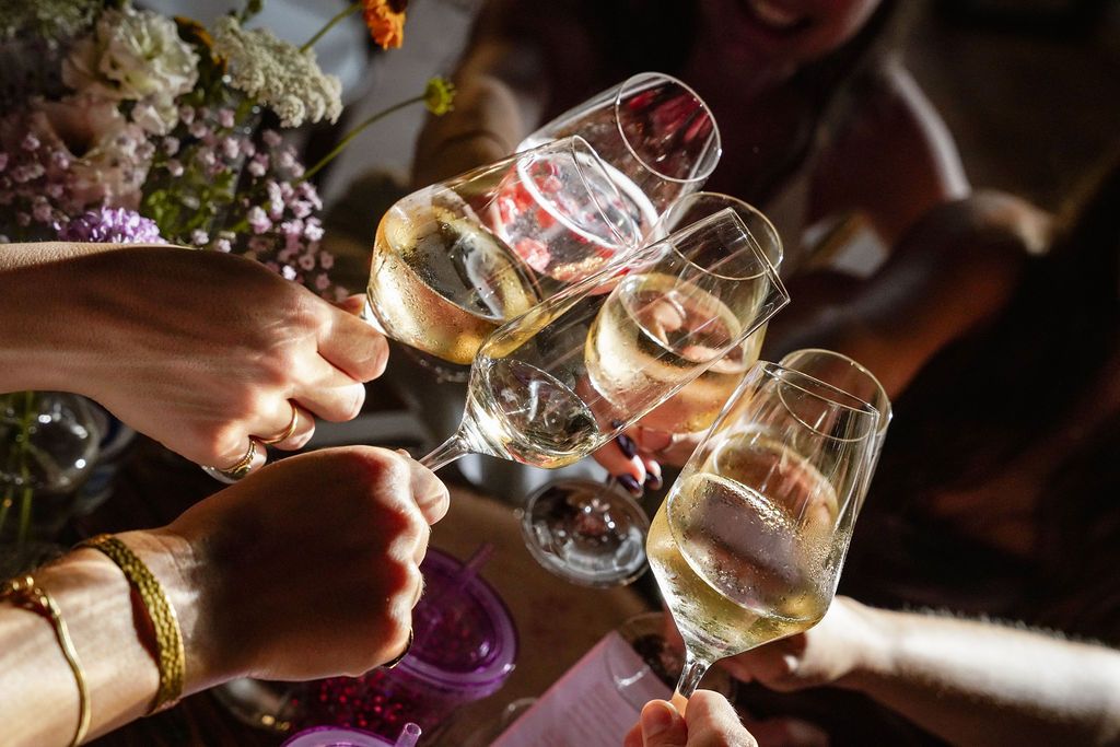 People toasting with wine glasses during a celebratory gathering at a restaurant or event.