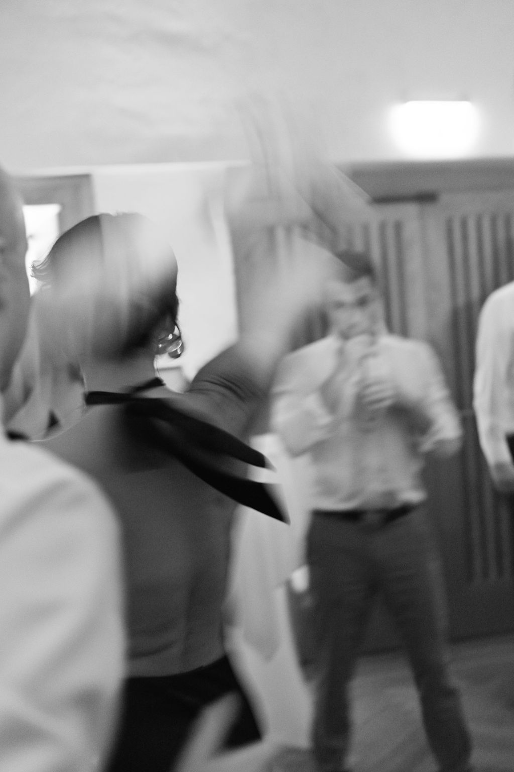 Blurry black and white motion photo of people dancing at what appears to be an indoor social gathering.