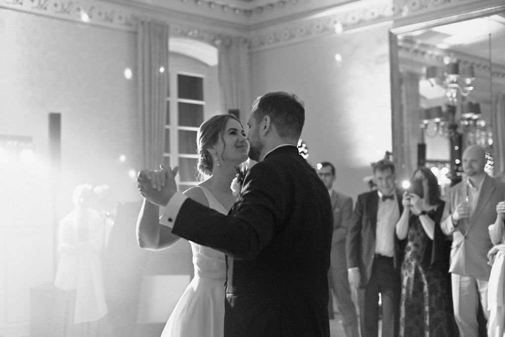 Black and white photo of a bride and groom sharing their first dance at an elegant wedding reception.