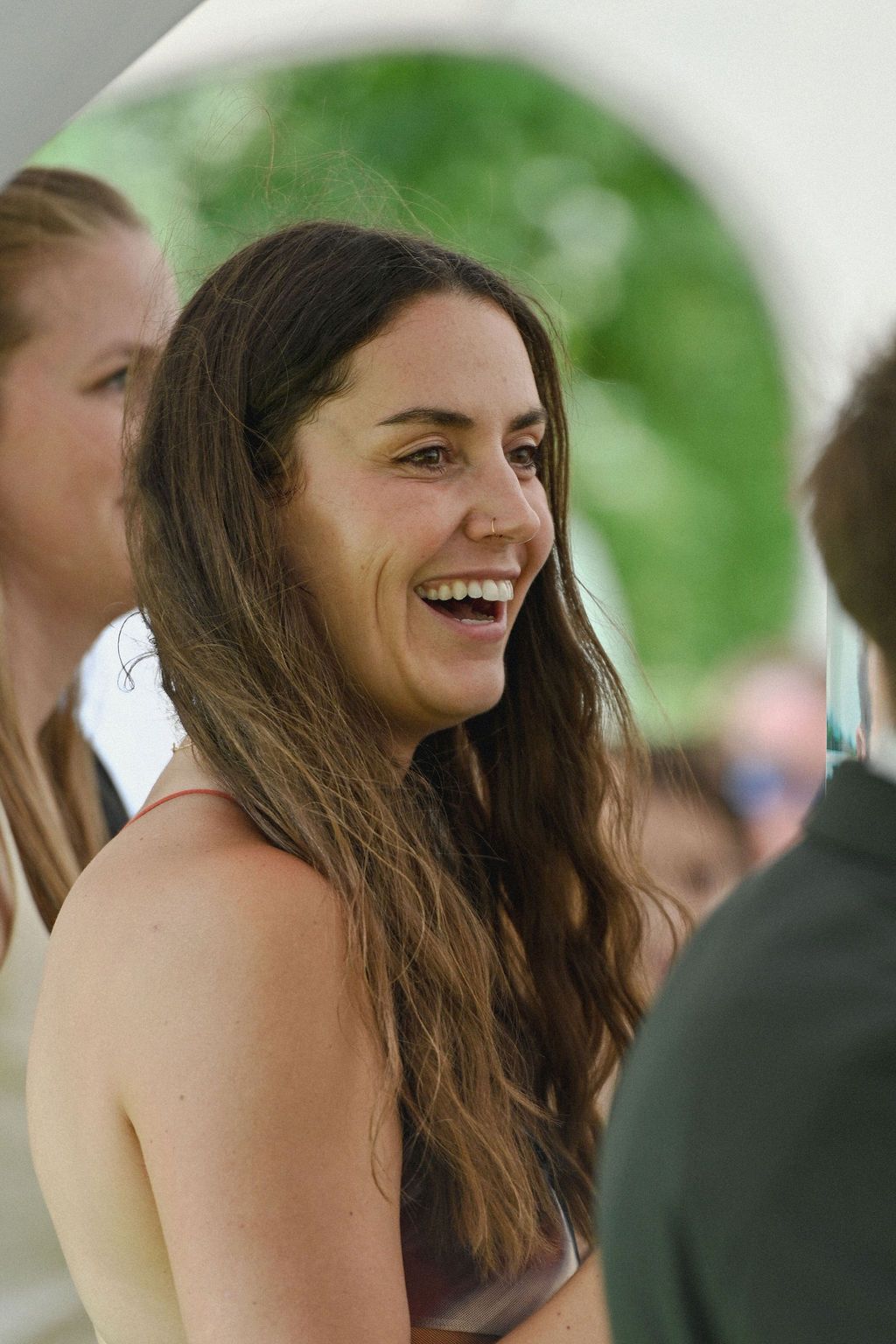 A sequence of candid shots shows a person with long brown hair laughing joyfully at an outdoor event.