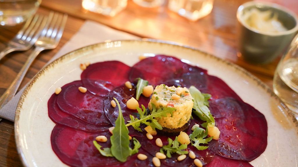 Artfully plated appetizers featuring colorful beet carpaccio with microgreens and edible flowers.