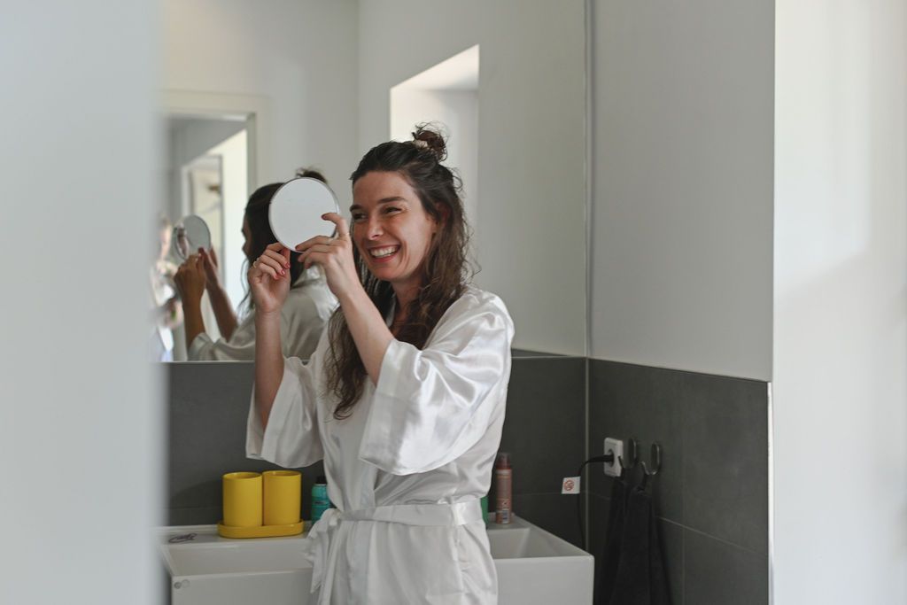 Four sequential photos show someone in a white robe applying skincare products in a bathroom mirror.