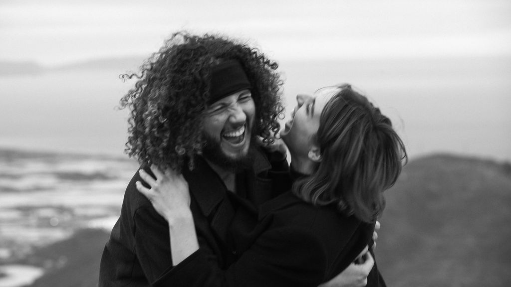A series of black and white photographs showing joyful embraces and laughter between people on a beach.