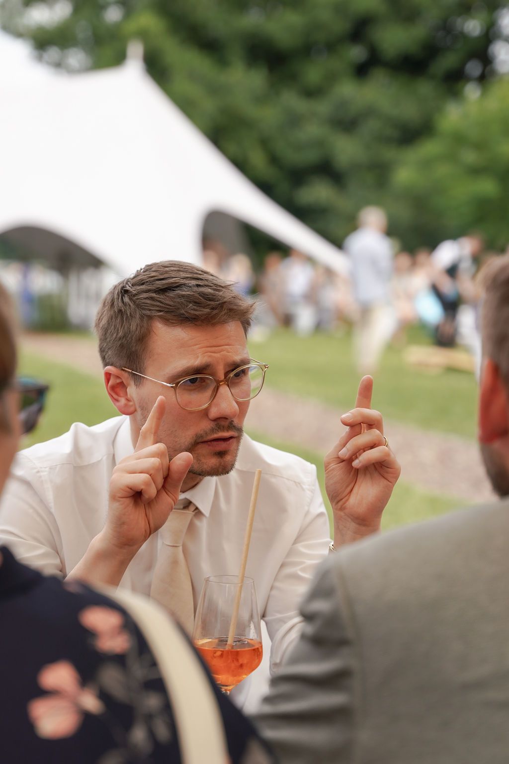 A sequence of four photos showing someone in a white suit jacket gesturing while having a conversation outdoors.