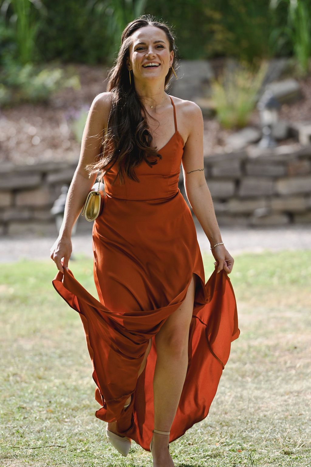 A person in a flowing rust-colored dress spins playfully outdoors in a series of dynamic movement shots.