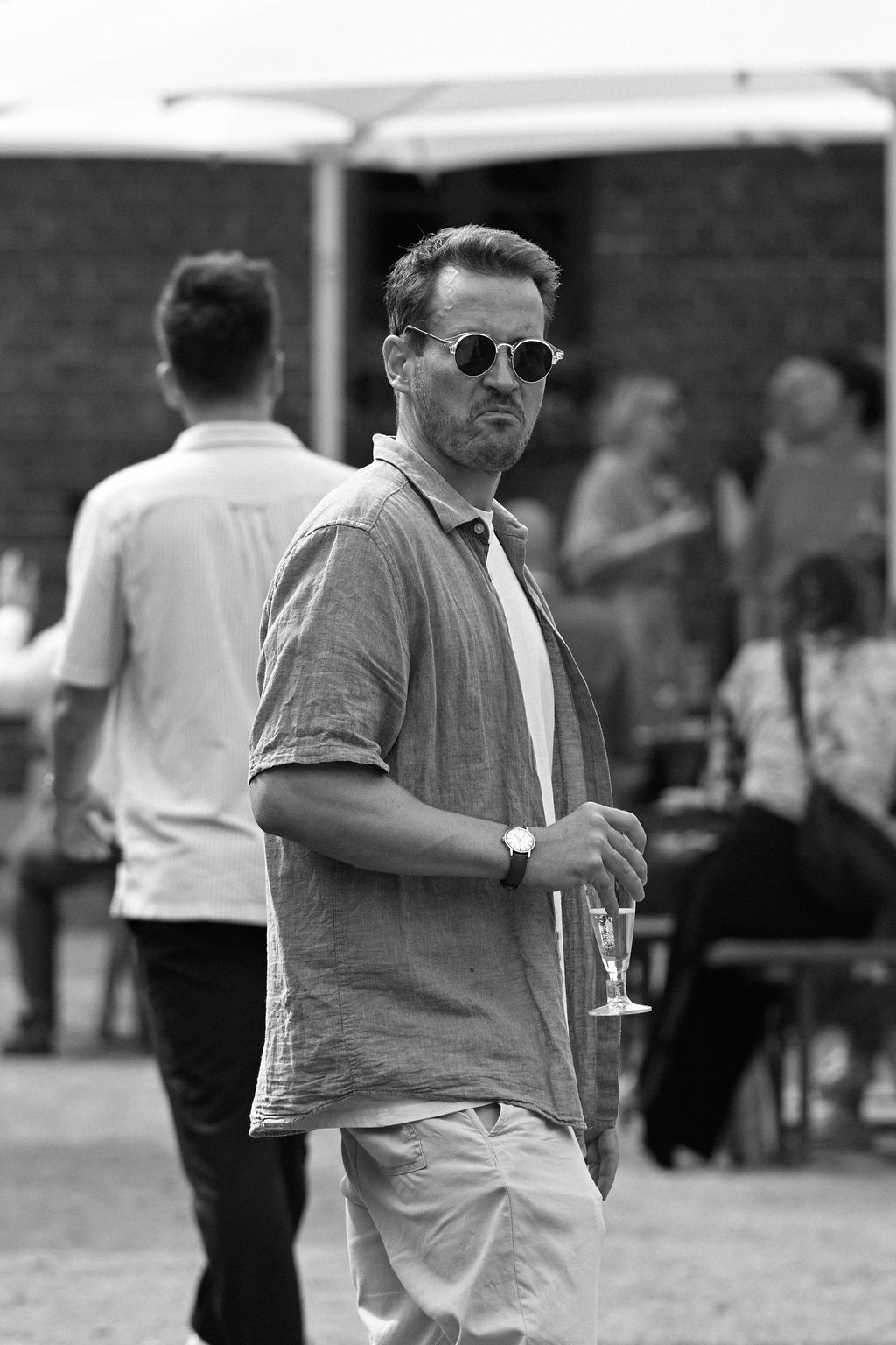 A sequence of black and white photos showing a person in sunglasses walking and turning while wearing casual attire.