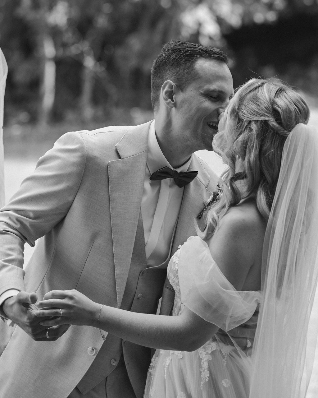 Black and white photo sequence showing a romantic kiss between newlyweds during an outdoor wedding ceremony.