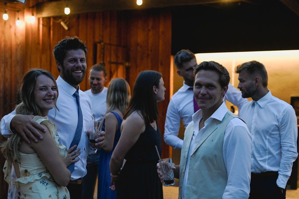 Wedding guests dance and celebrate during an evening reception in a warmly lit venue.