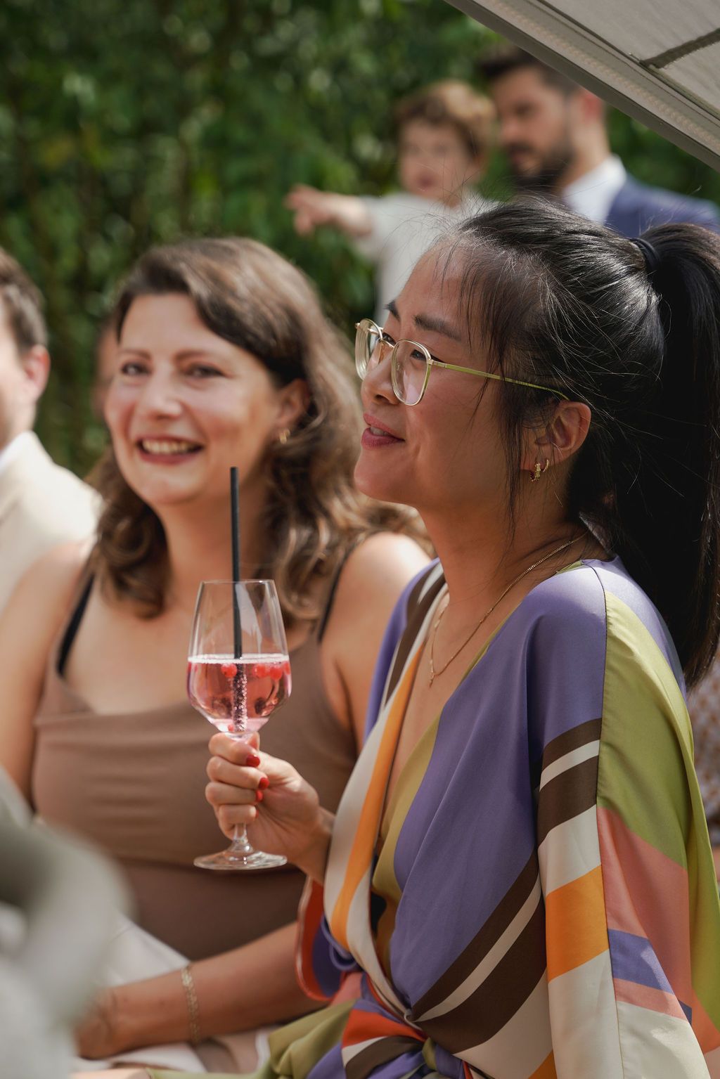 A group of guests enjoying drinks and laughter during an outdoor celebration.