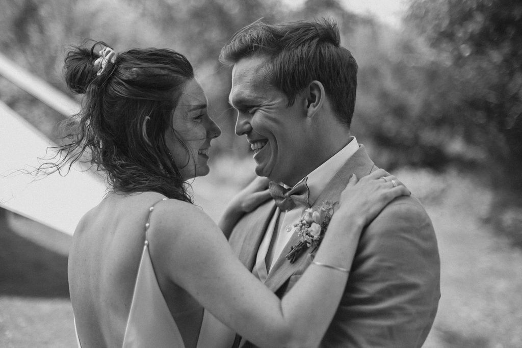 Black and white wedding photos capturing tender moments between newlyweds in a natural outdoor setting.