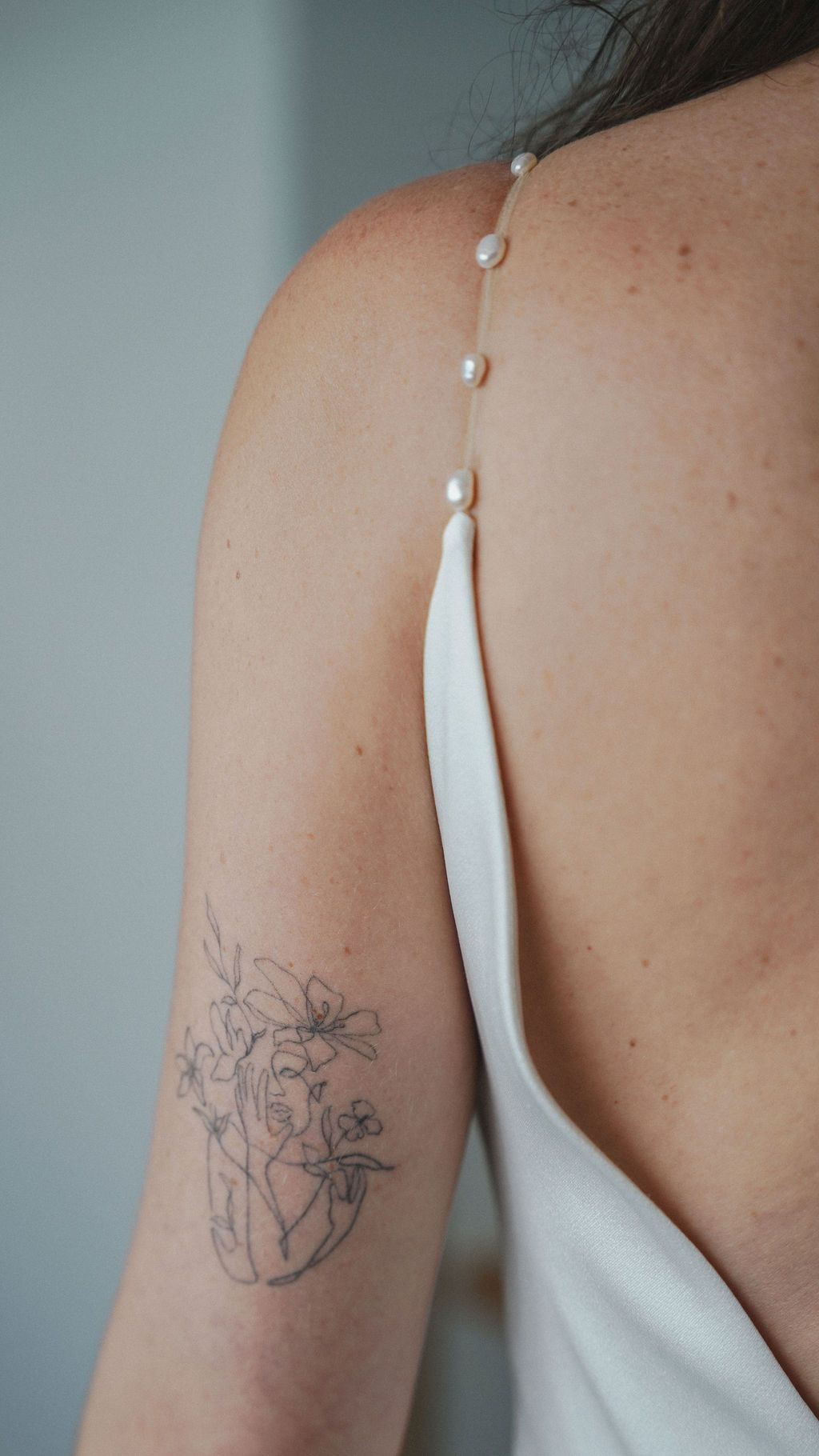 Close-up view of a delicate floral anatomical heart tattoo on an arm with white dress strap visible.