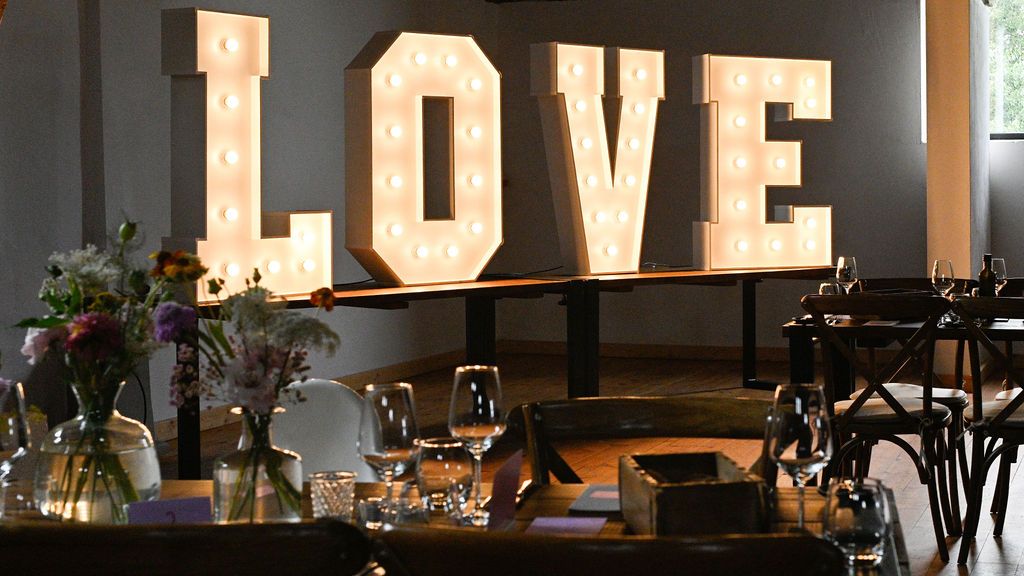 Modern restaurant interior with illuminated LOVE sign and stylish dining tables arranged in a dimly lit space.