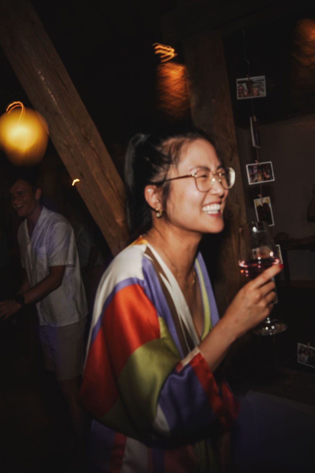 People enjoying drinks and socializing at a dark indoor party venue with warm ambient lighting.