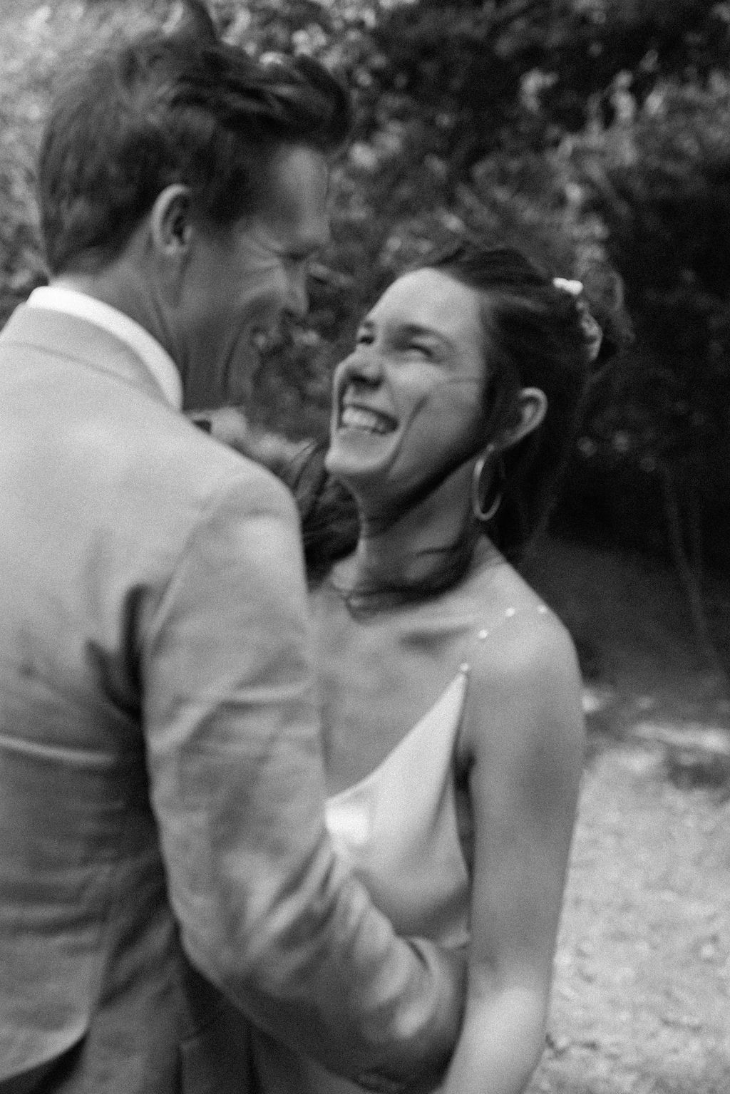A series of black and white photos showing joyful laughter and playful interaction between two people outdoors.