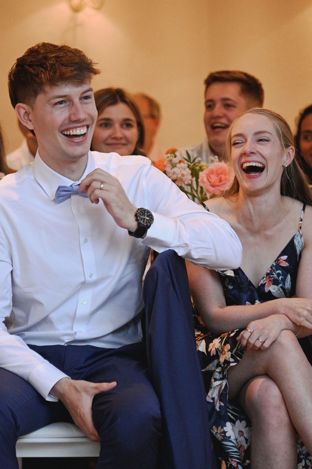 Group of people sitting together on a couch sharing laughter and joyful moments at a social gathering.