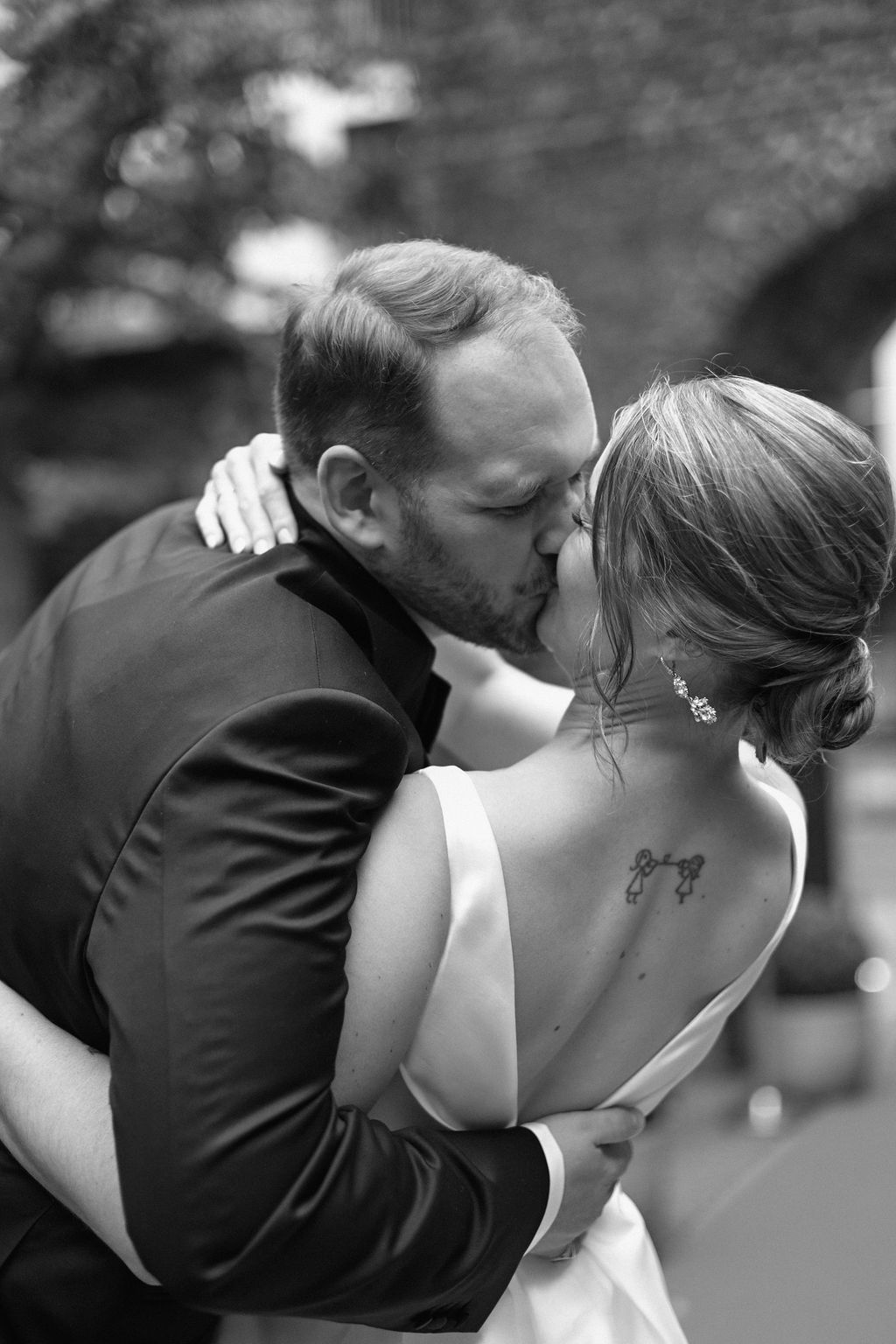 A romantic black and white photo series showing a couple sharing tender kisses in an outdoor setting.