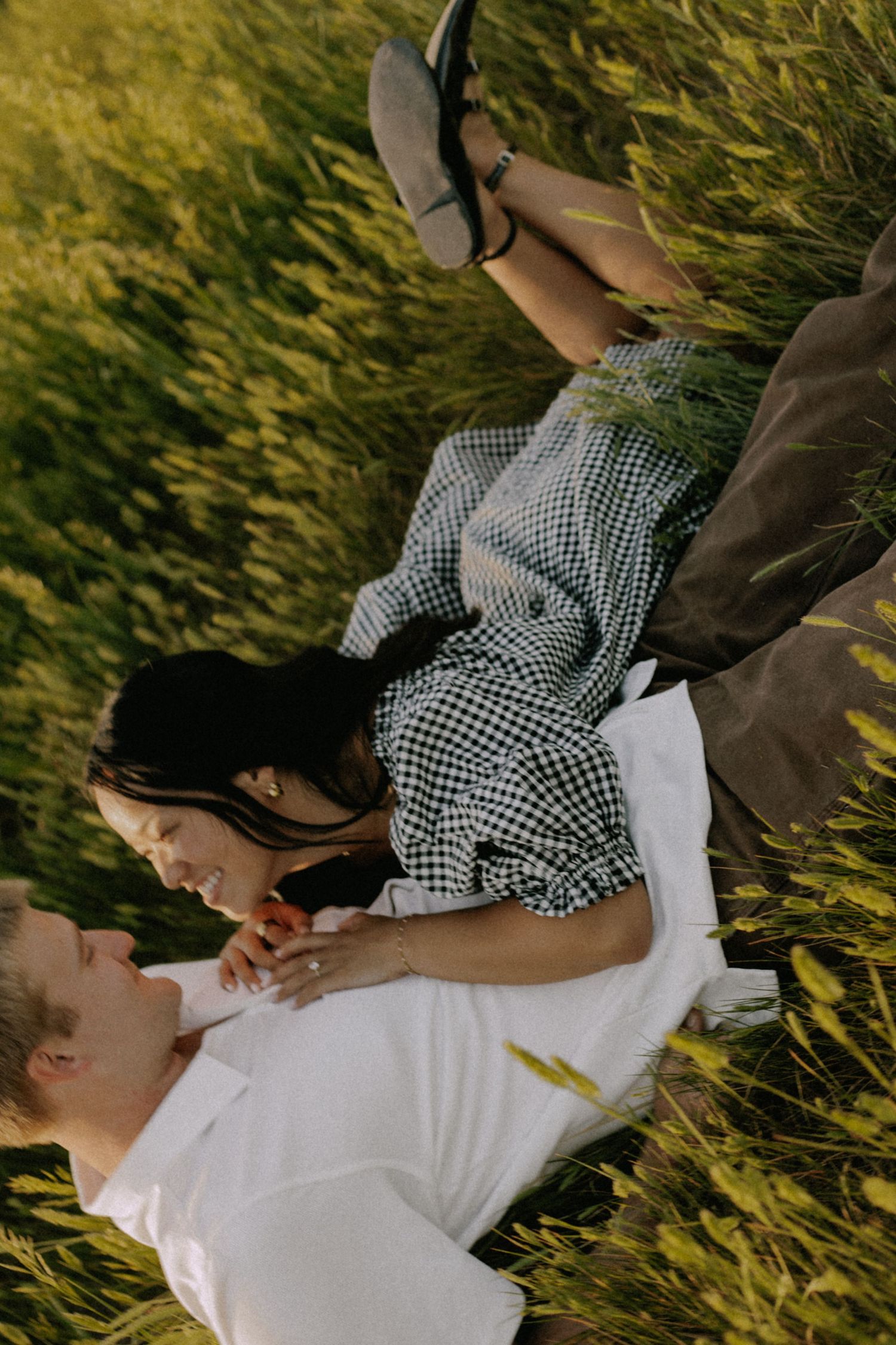 A couple lying in golden grass sharing intimate moments during sunset.