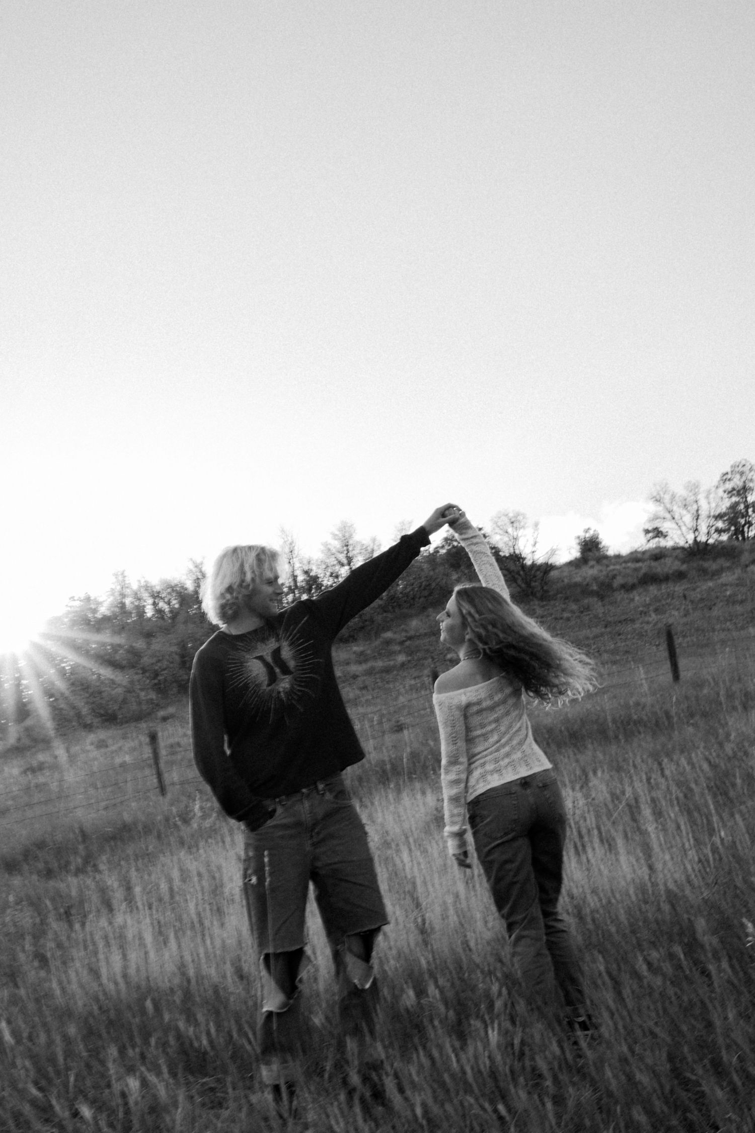 Silhouettes of people walking through a grassy field at sunset.